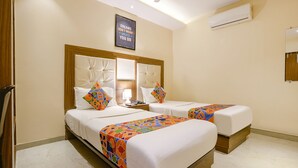 A hotel room with two beds, a mirror, a framed motivational quote, an air conditioner, and a wooden floor. - Via Wynd (Mumbai)