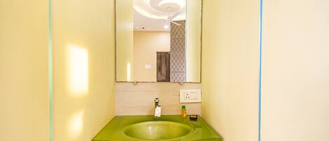 A bathroom with a green sink, a mirror, and a ceiling light fixture.