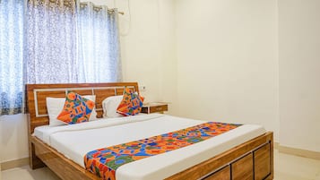 A neatly made bed with a patterned bedspread, a wooden headboard, and two pillows with geometric designs.