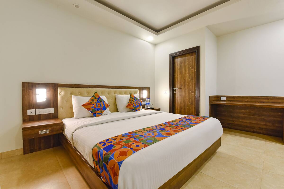 Quarto de hotel bem arrumado com uma cama grande, cabeceira de madeira, mesas de cabeceira e um banco de madeira.