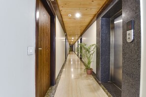 A hallway with wooden ceiling, a potted plant, and an elevator. - Fabhotel The Palm (Jaipur)
