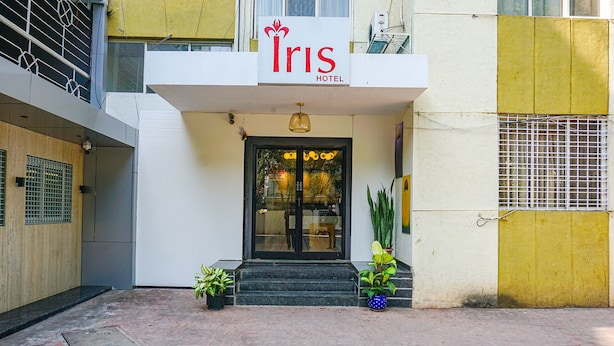 Entrada del Hotel Iris con un cartel sobre la puerta, plantas en macetas a cada lado y una reja metálica a la derecha.