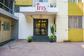 The Iris Hotel entrance with a sign above the door, potted plants on either side, and a metal gate to the right. - Fabhotel Irish (Pune)