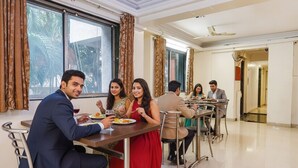 A dining area with tables and chairs, large windows with curtains, and a clean, modern interior. - Fabhotel Royal Samrat (Pune)