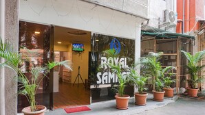 A building entrance with a sign reading "ROYAL SAMSUNG" and several potted plants in front. - Fabhotel Royal Samrat (Pune)