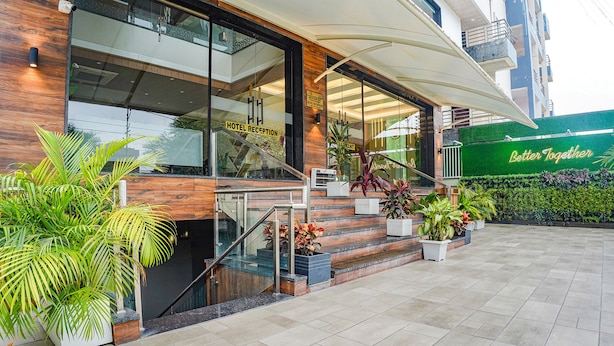 A hotel reception area with a modern design, including a glass entrance, wooden accents, and a staircase leading to the entrance. - Fabhotel Prime Ocean Breeze (Bhopal)
