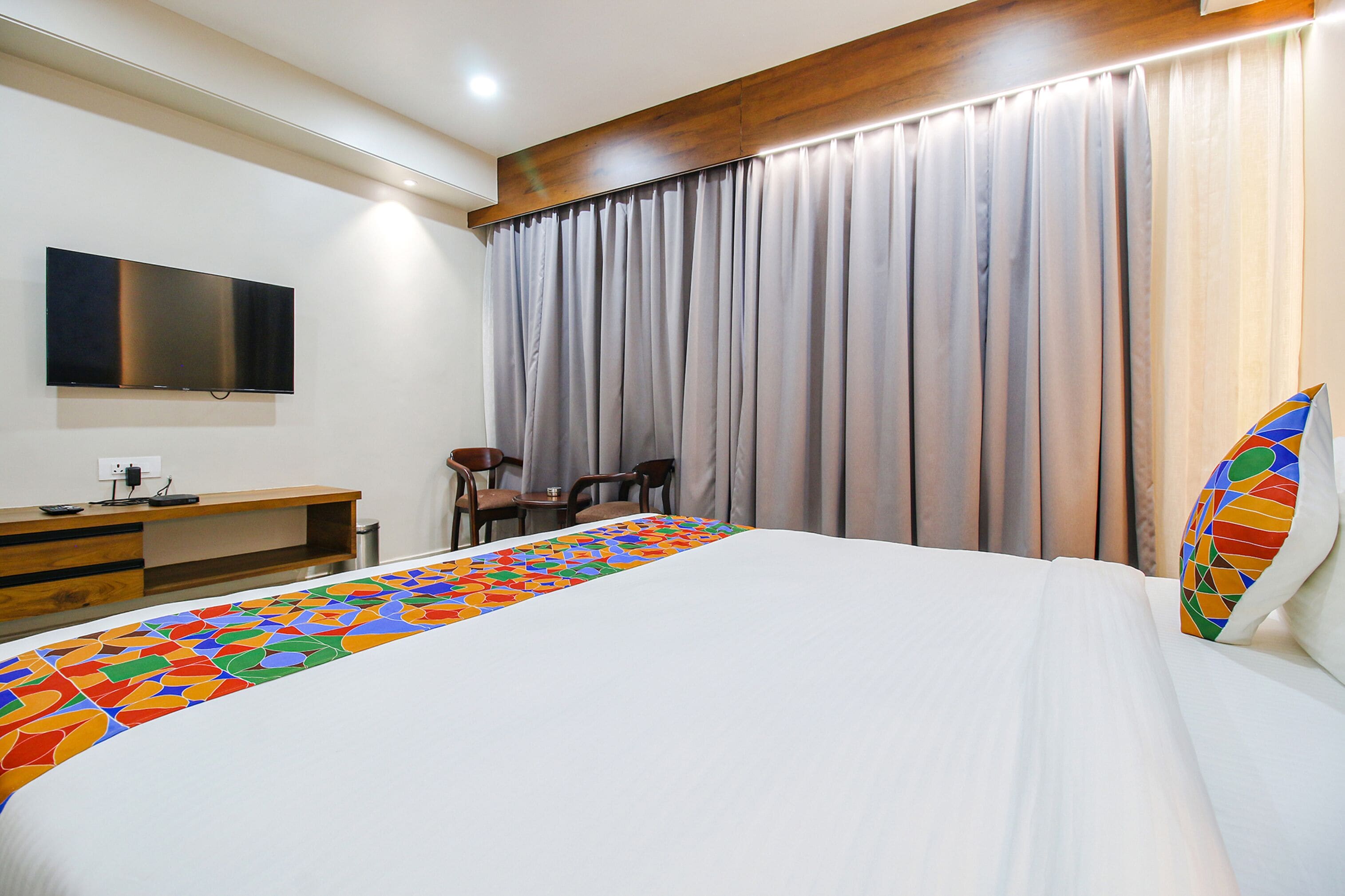 Ein Hotelzimmer mit Bett, Wandfernseher, Schreibtisch und Stuhl.