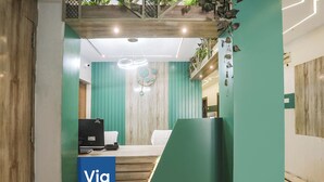 Un comptoir d’accueil avec une enseigne « Via », un bureau en bois, un ordinateur et une chaise.