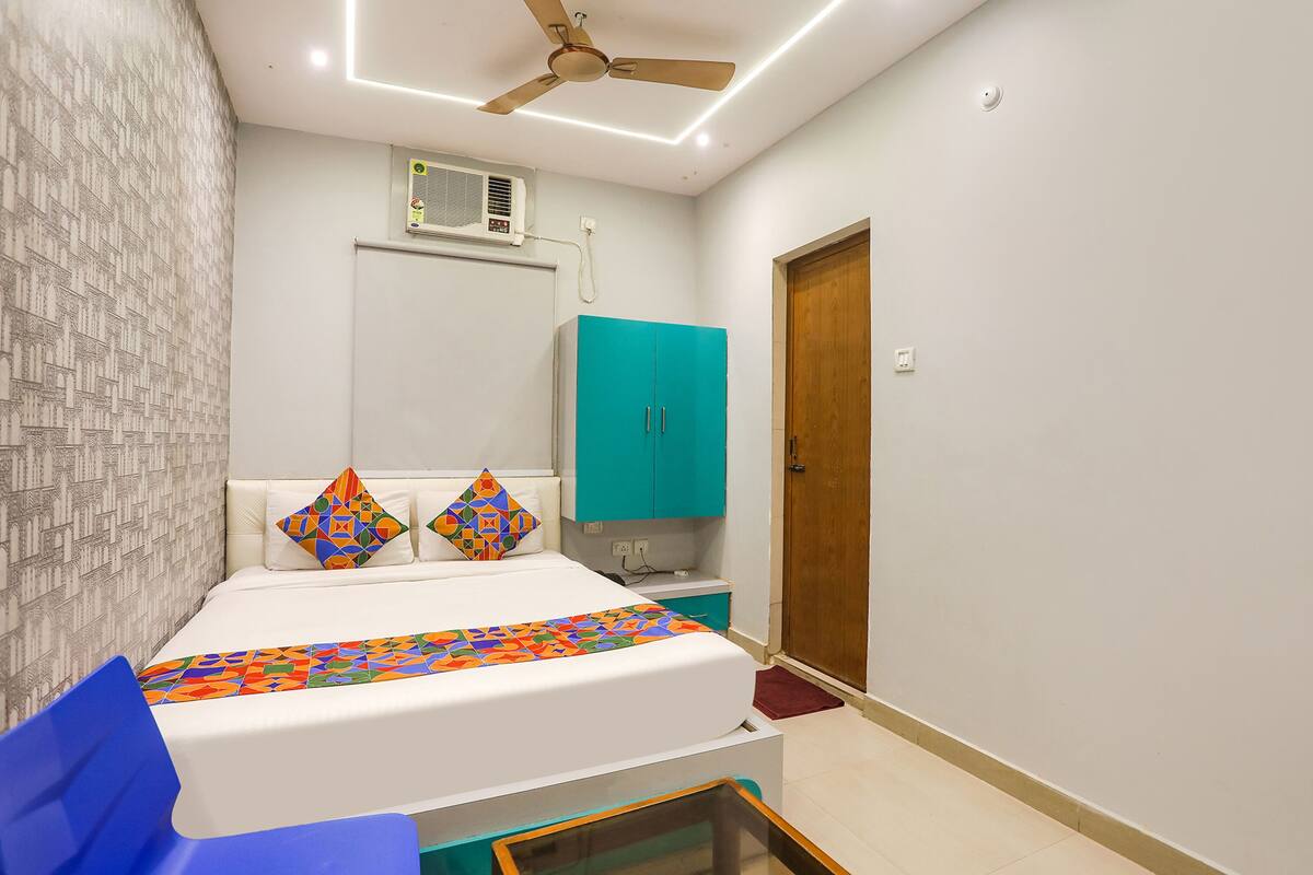 Une chambre à coucher avec un lit, un ventilateur de plafond, une armoire turquoise et une porte en bois.