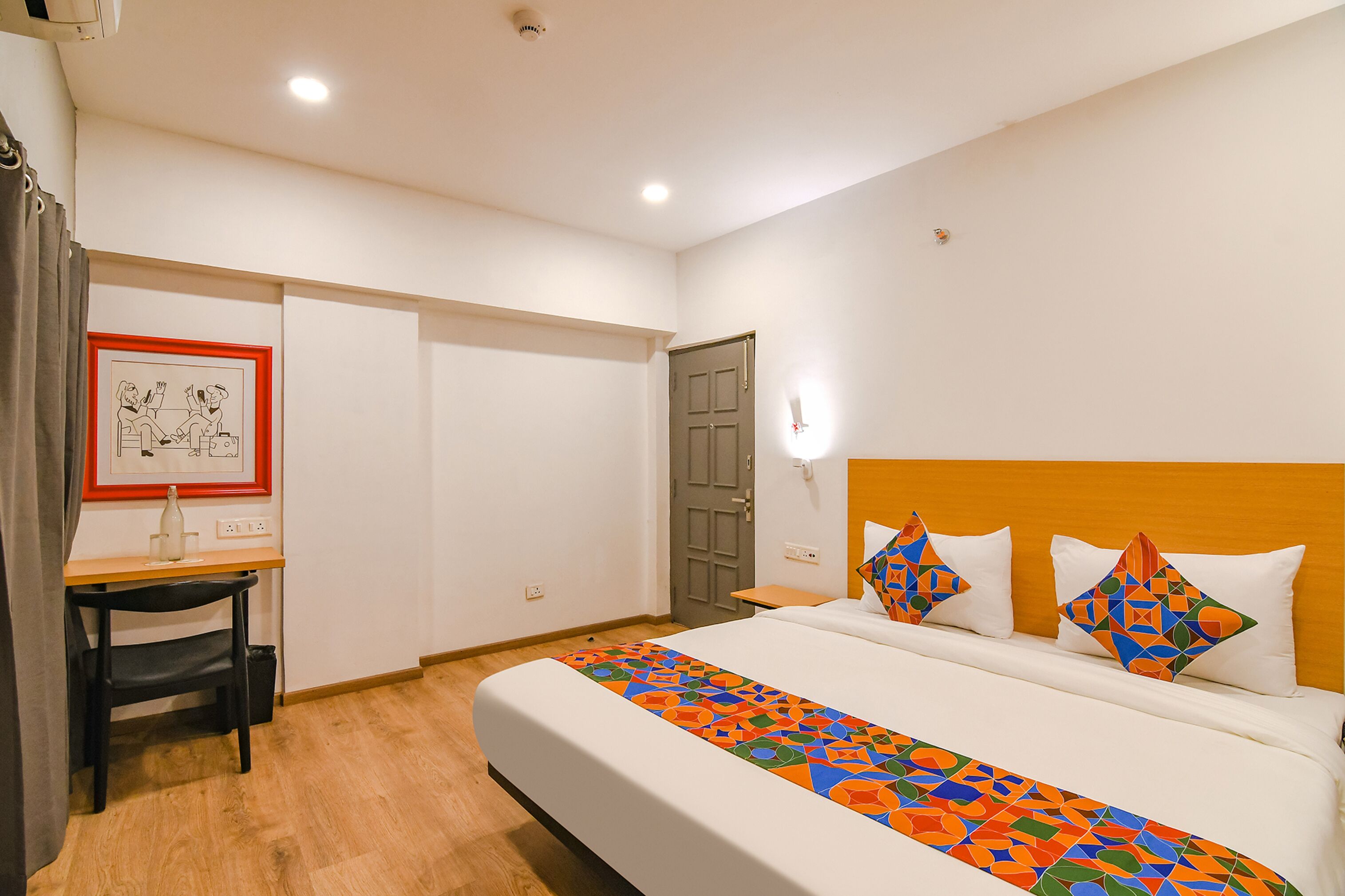 A hotel room with a bed, a desk, and a chair.