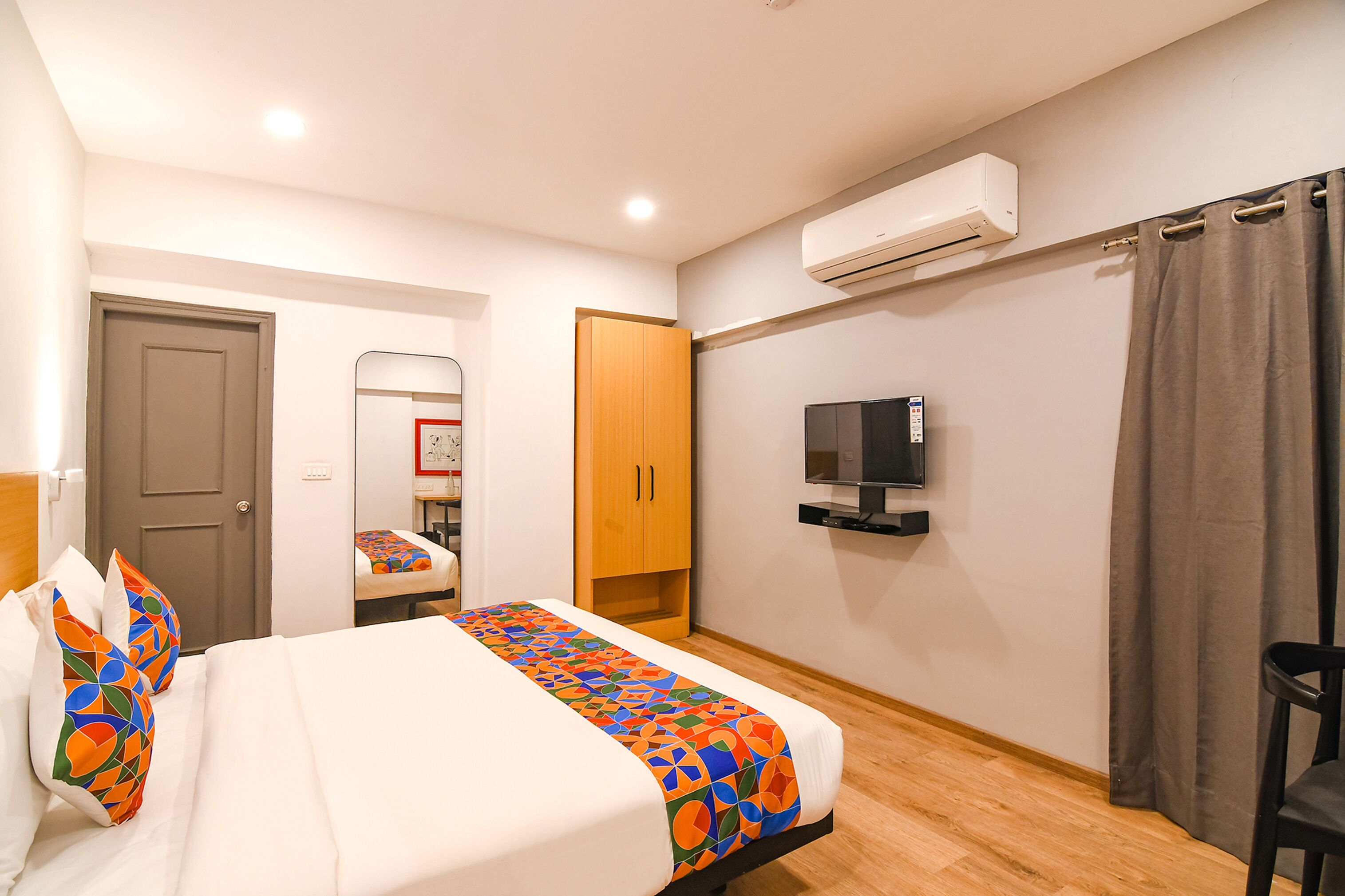 Ein Hotelzimmer mit Bett, Fernseher, Klimaanlage, Kleiderschrank und Tür.