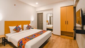 A hotel room with a bed, a wooden wardrobe, a mirror, and a television. - Fabhotel Sayeeda International (Kolkata)