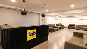 A hotel reception area with a black reception desk, multiple sofas, and ceiling lights. - Fabhotel Sayeeda International (Kolkata)