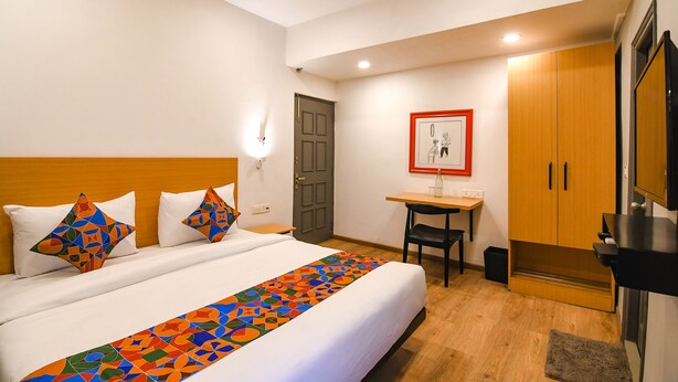 A hotel room with a bed, a desk, a chair, a wardrobe, and a television. - Fabhotel Sayeeda International (Kolkata)