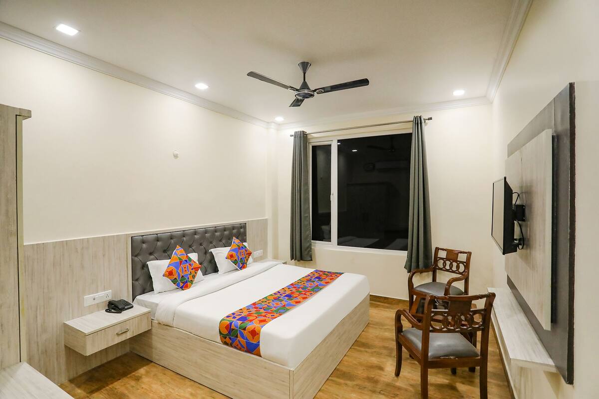 A neatly arranged bedroom with a bed, bedside table, chair, and a TV mounted on the wall.