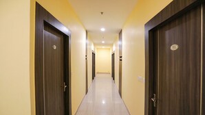 A long, narrow hallway with dark wooden doors on both sides, leading to a bright room at the end. - FabHotel Trijal Inn (Lucknow)