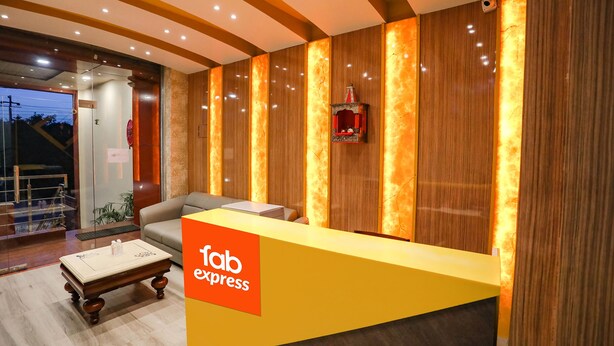 A reception area with a 'fab express' sign, a sofa, a small table, and a decorative item on the wall. - FabHotel Trijal Inn (Lucknow)