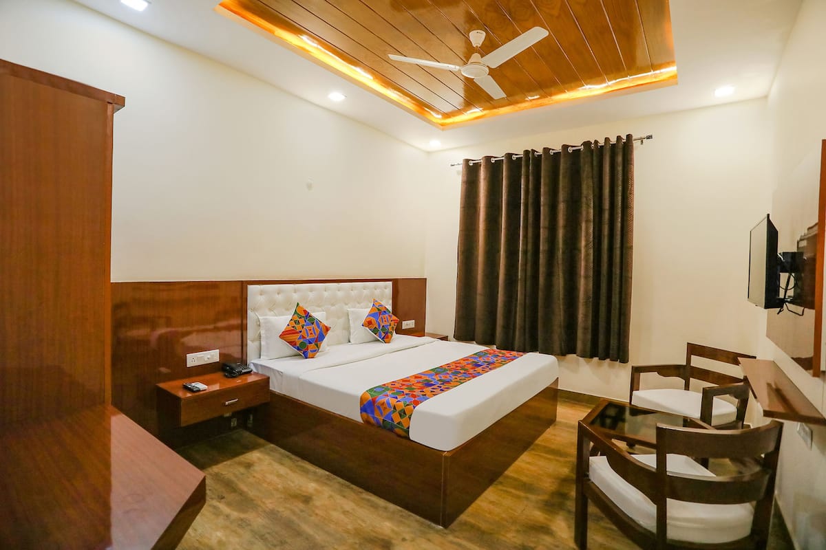 A hotel room with a bed, bedside table, nightstand, and a desk with chairs.