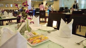 Une table à manger dressée avec des serviettes blanches, un vase rempli de fleurs et un menu.
