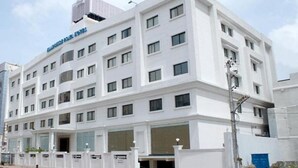 Un hôtel à plusieurs étages, doté d’une façade blanche, de nombreuses fenêtres et d’une enseigne bien visible indiquant qu’il s’agit d’un hôtel.