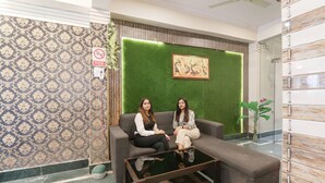 Un hall con papel tapiz estampado, una pared verde con obras de arte, un sofá y una mesa de centro.