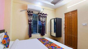Una habitación de hotel con cama, ventana con cortinas, armario y puerta.