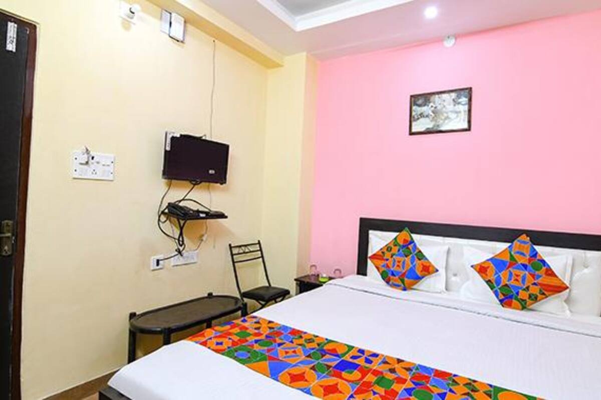A hotel room with a bed, a television mounted on the wall, and a small table.