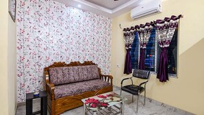 Una sala de estar con un sofá, una silla, una mesita y un ventanal con cortinas.