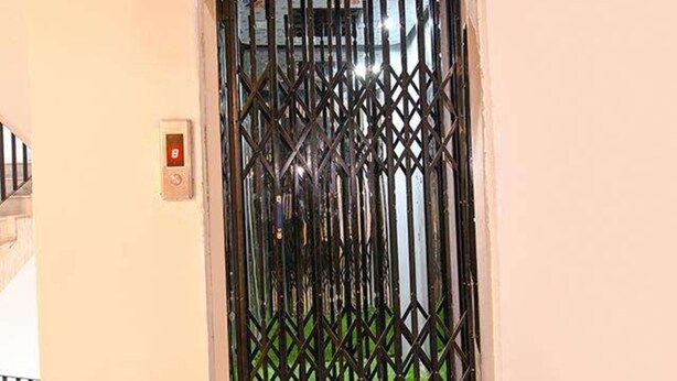 Una puerta con una reja metálica de seguridad y un sistema de intercomunicación instalado en la pared.