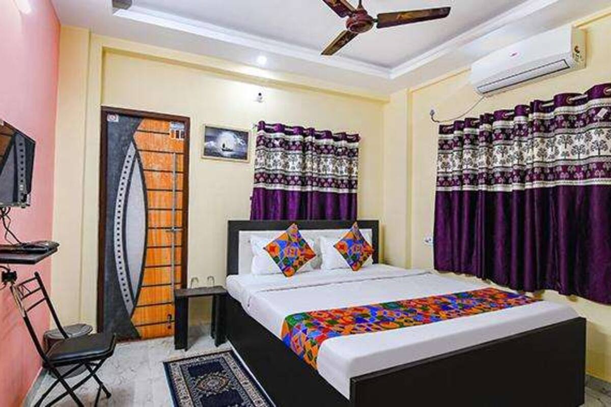 A bedroom with a bed, a chair, a desk, a ceiling fan, and curtains.