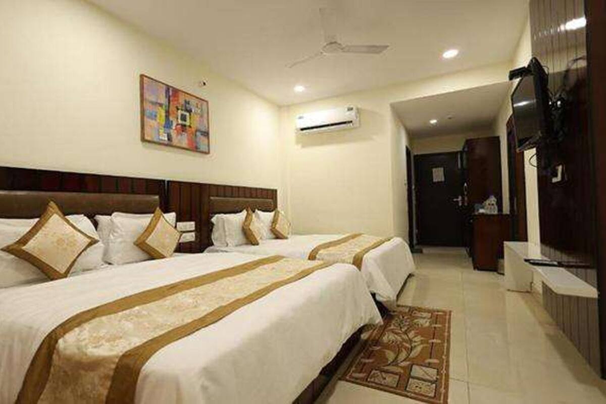 A hotel room with two beds, a ceiling fan, an air conditioning unit, and a painting on the wall.