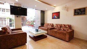 A modern living room with two sofas, a coffee table, and a flat-screen TV mounted on the wall. - Fabhotel Red Coral (Haridwar)