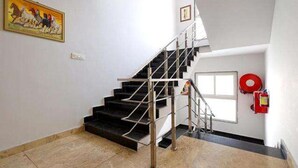 A staircase with metal railings, a fire extinguisher mounted on the wall, and a framed picture on the wall. - Fabhotel Red Coral (Haridwar)