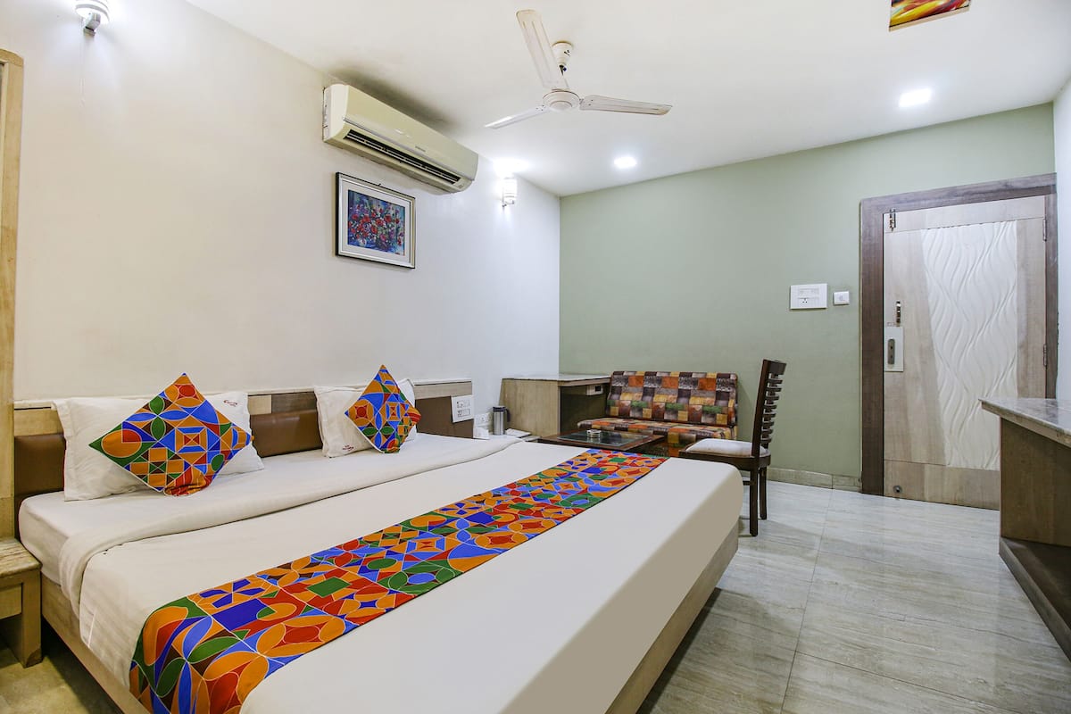 Quarto de hotel com uma cama, uma cadeira, uma escrivaninha, ar condicionado e uma porta.