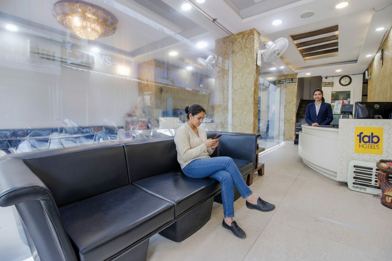 Een hotel receptie met een wachtruimte, een receptiebalie en een receptionist.