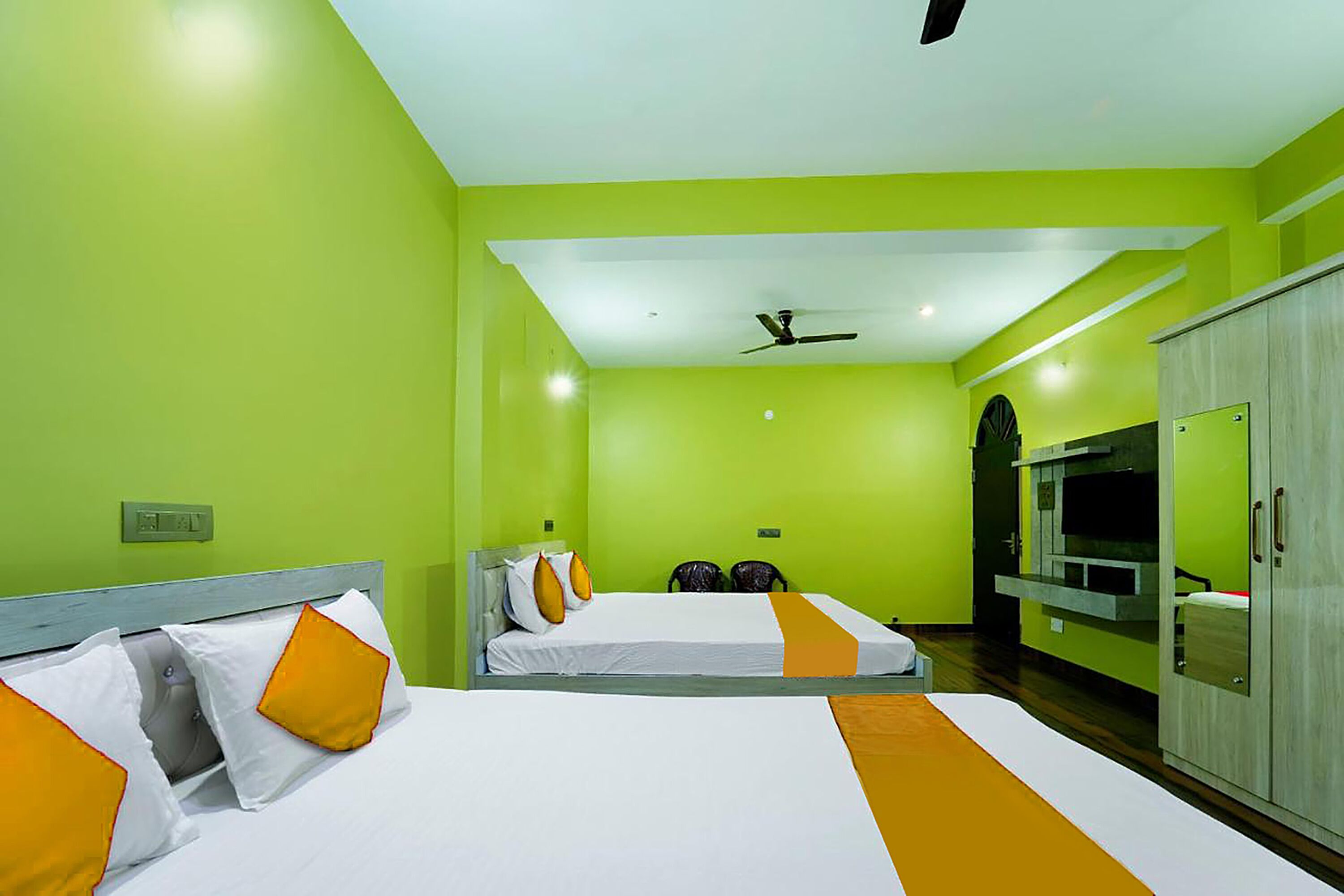 A hotel room with two beds, a ceiling fan, and a wardrobe.