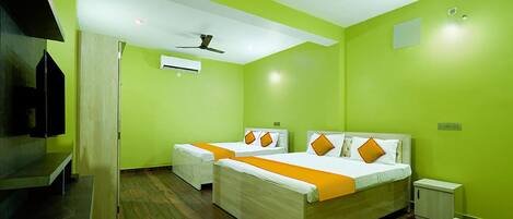 A hotel room with two beds, a TV, and a ceiling fan.