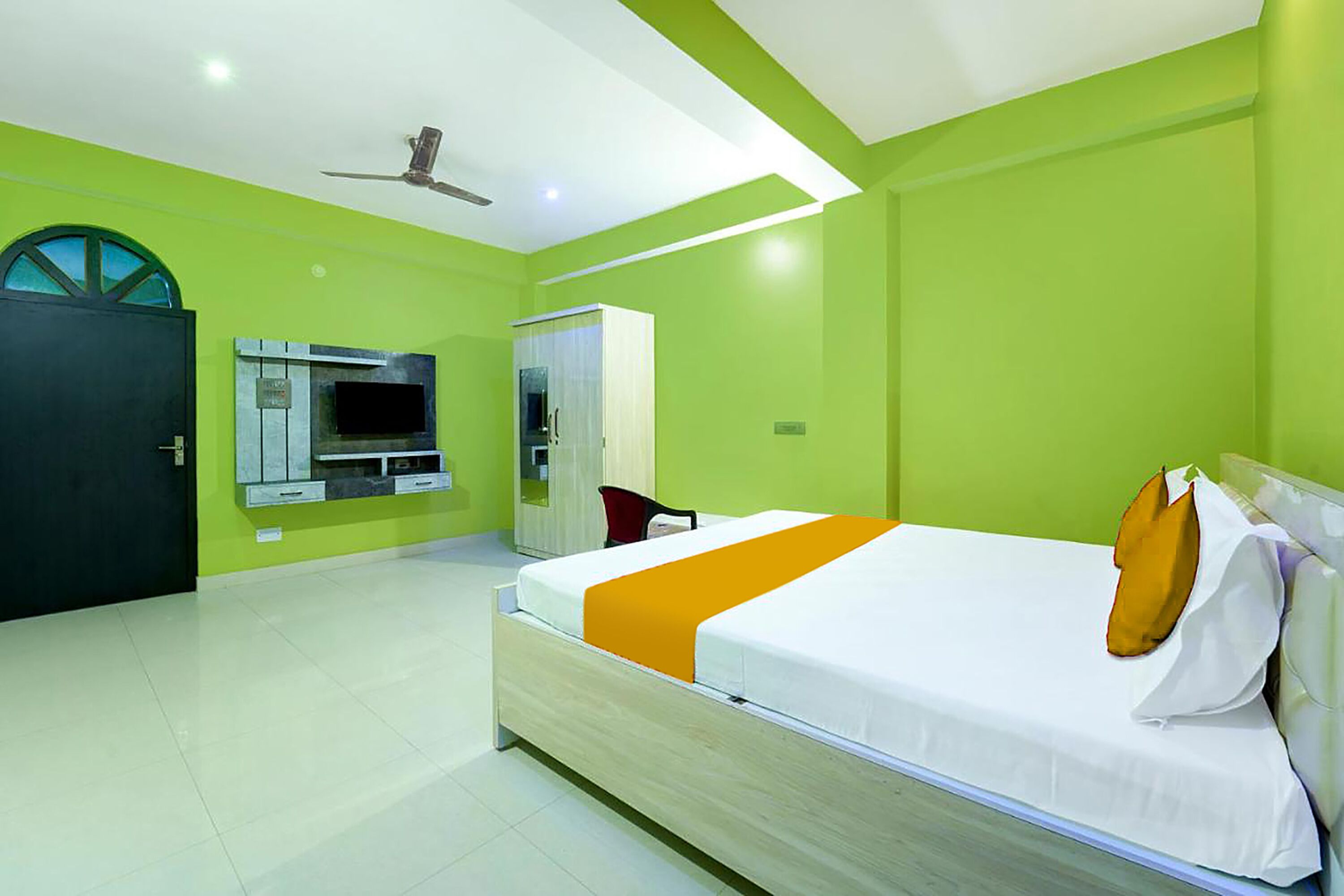 Une chambre d’hôtel avec un lit, une télévision, une armoire et une porte.