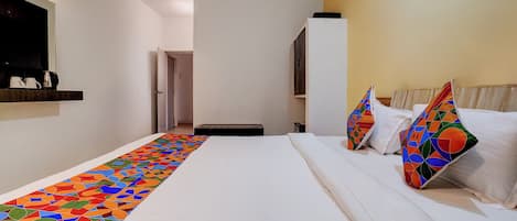 A hotel room with a bed, a colorful runner, a wardrobe, and a door leading to another room.