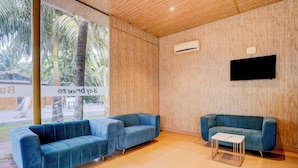 A modern room with two blue sofas, a small white table, and a mounted TV. - Oriva Shourya Residency (Pune)