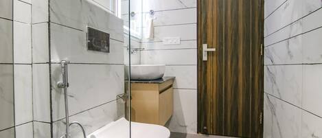 A modern bathroom with a glass-enclosed shower, a white toilet, and a wooden vanity with a sink.