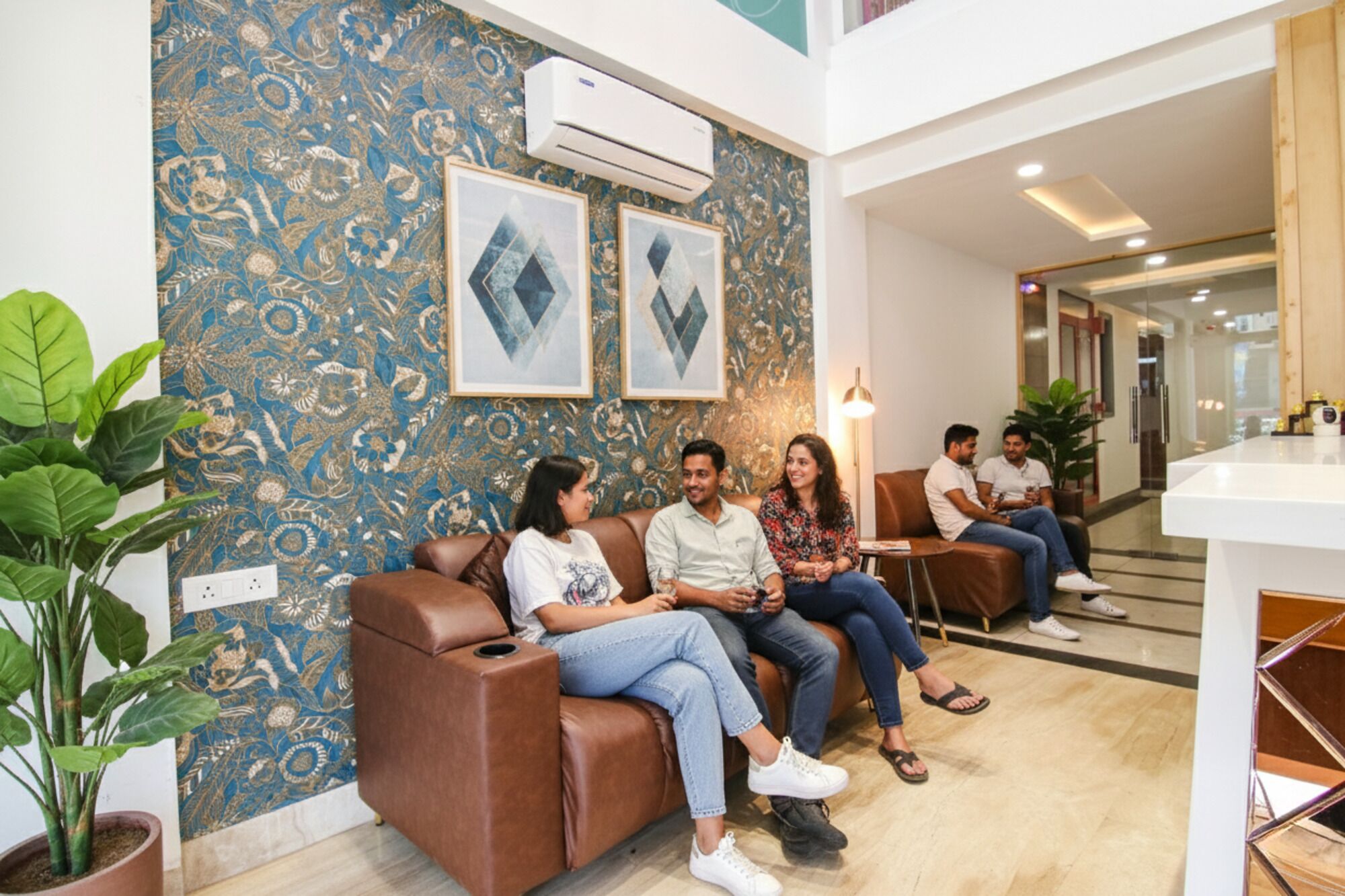 A lobby with a patterned wall, a brown leather sofa, and a reception desk.