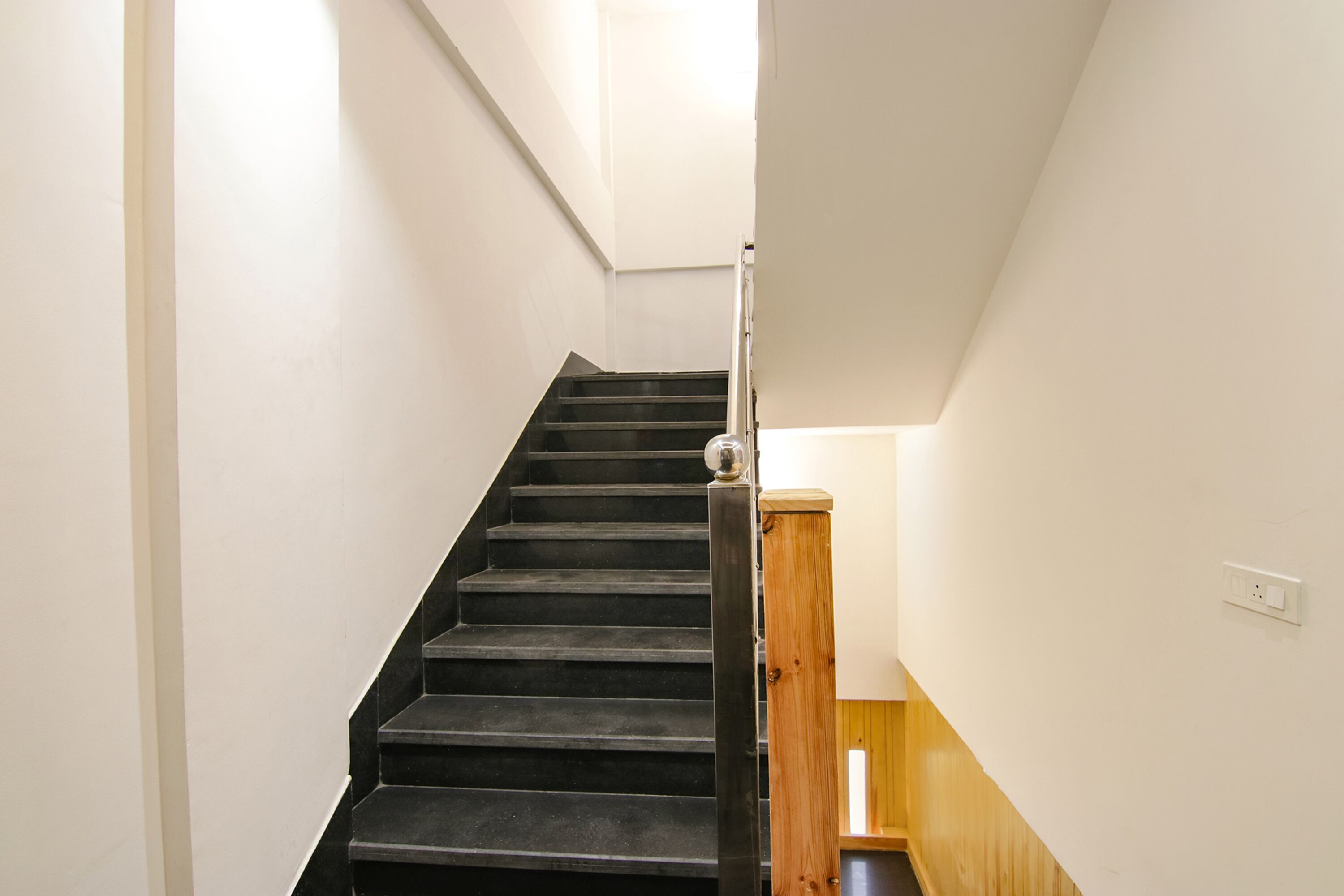 A staircase with black steps and a wooden handrail.