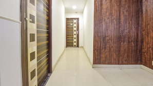 Un pasillo con una puerta de madera, una puerta con diseño y un suelo de baldosas.