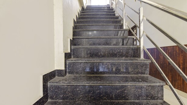 Un conjunto de escalones de mármol con barandas de metal, que conducen hacia arriba en un edificio.