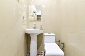 A small, modern bathroom with a white sink, toilet, and mirror. - Fabexpress Mohan Vilas Residency (Dehradun)