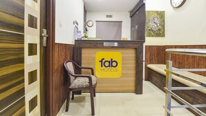 Un mostrador de recepción con un letrero que dice "fab hotels", un reloj y un adorno en la pared.