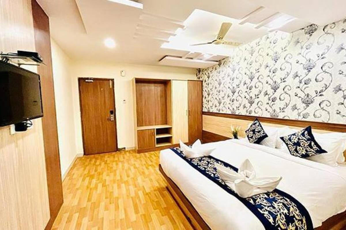 Ein Hotelzimmer mit einem Bett, einem Kleiderschrank, einem Fernseher und einem Wandteppich mit Muster.