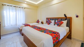 A hotel room with two beds, a ceiling fan, and a window with curtains. - FabHotel Happy Home Stay (Bengaluru)