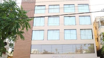 A multi-story hotel named Centella with a modern facade, multiple windows, and a visible reflection of the surrounding area.